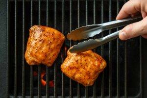 placing marinated chicken on oiled grill grates